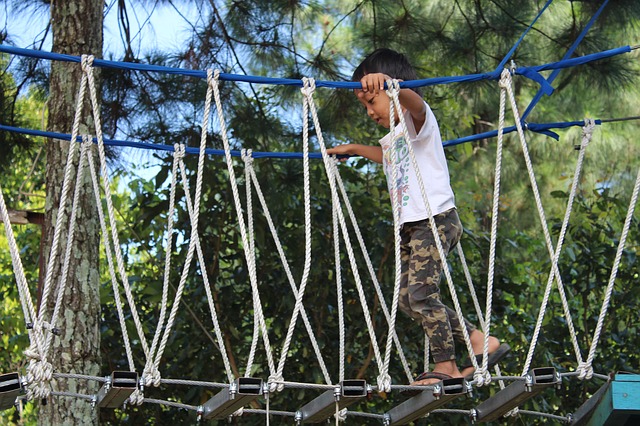 Little boy crossing a rope bridge on a playground