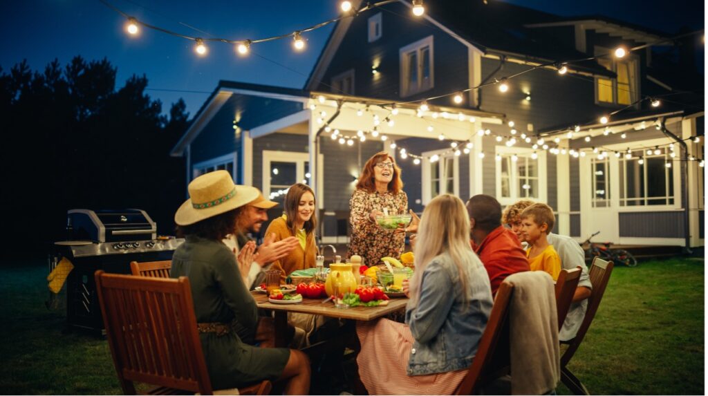 group of friends enjoying outdoor bbq in backyard with string lights